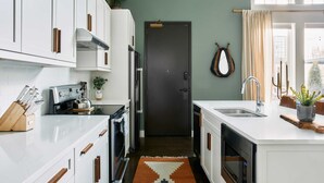 A modern kitchen with white cabinets, a built-in oven, a coffee machine, and a sink. - Stay In The Heart Of 12 South, Designer Penthouse  |  1 of 7 Themed Lofts at Cowrite, Find Coffee and Tacos Downstairs, Complimentary Spin Class, Walk to Shopping in 12 South, 10 Minutes to Broadway, Parking, 24 Hr Hospitality (Nashville)