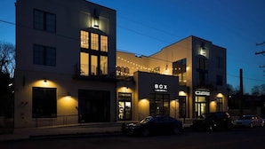 A modern building with a 'BOX' sign, multiple windows, and a street view with parked cars. - Stay In The Heart Of 12 South, Designer Penthouse  |  1 of 7 Themed Lofts at Cowrite, Find Coffee and Tacos Downstairs, Complimentary Spin Class, Walk to Shopping in 12 South, 10 Minutes to Broadway, Parking, 24 Hr Hospitality (Nashville)