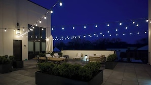 An outdoor patio area with string lights, seating, and planters. - Stay In The Heart Of 12 South, Designer Penthouse  |  1 of 7 Themed Lofts at Cowrite, Find Coffee and Tacos Downstairs, Complimentary Spin Class, Walk to Shopping in 12 South, 10 Minutes to Broadway, Parking, 24 Hr Hospitality (Nashville)