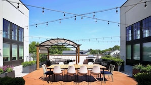 A rooftop patio with a wooden table and chairs, surrounded by planters and a pergola. - Johnny Cash Inspired 2-Suite Loft In 12 South      |         1 of 7 Themed Lofts at Cowrite, Find Coffee and Tacos Downstairs, Complimentary Spin Class, Walk to Shopping in 12 South, 10 Minutes to Broadway, Parking, 24 Hr Hospitality (Nashville)