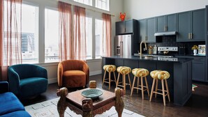 Una cocina moderna con armarios oscuros, un refrigerador de acero inoxidable y una isla central con taburetes.