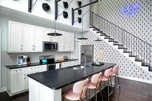 Una cocina moderna con armarios blancos, encimera negra y una isla central con taburetes de bar.