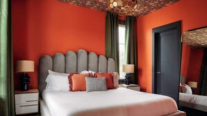 Une chambre d’hôtel avec un grand lit, une table de chevet avec une lampe, une porte et un miroir.