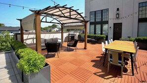 An outdoor patio area with a wooden pergola, a table and chairs, and potted plants. - King Penthouse in 12 South, 3 Miles To Broadway   |   Soaring Ceilings, 1 of 7 Themed Lofts at Cowrite, Find Coffee and Tacos Downstairs, Complimentary Spin Class, Walk to Shopping in 12 South, 10 Minutes to Broadway, Parking, 24 Hr Hospitality (Nashville)