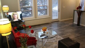 Ein Wohnzimmer mit Glastisch, rotem Sofa und Fernseher.