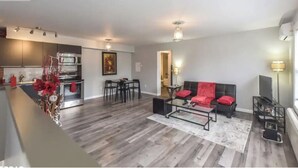 Ein modernes Wohnzimmer mit einem schwarzen Sofa, einem Couchtisch und einem Essbereich mit Tisch und Stühlen.
