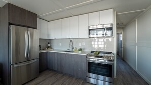 A modern kitchen with stainless steel appliances, white cabinetry, and a wooden floor. - Suite 206: Beautiful 2-Bedroom Beachfront Suite (Wainfleet)