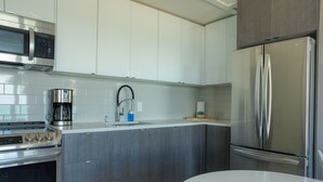 A modern kitchen with grey cabinetry, stainless steel appliances, and a white countertop. - Suite 206: Beautiful 2-Bedroom Beachfront Suite (Wainfleet)