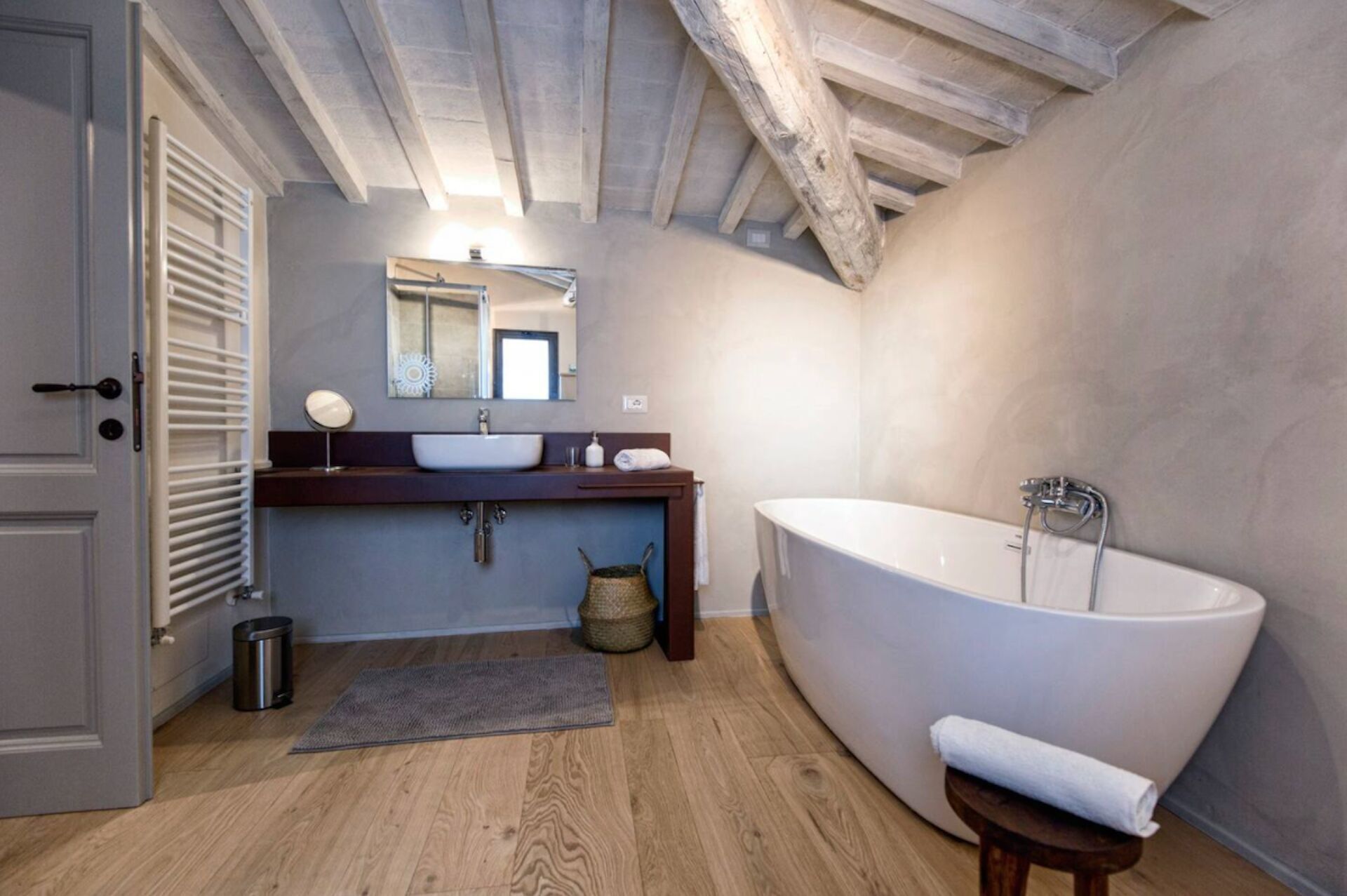 A modern bathroom with a freestanding bathtub, a wooden vanity, and a large mirror.