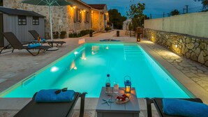 Piscina com espreguiçadeiras e mesa com comodidades.