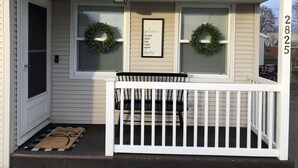 A house with a porch, two wreaths, a welcome sign, and a mailbox.