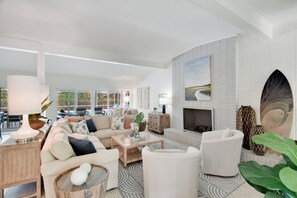 Amplia sala de estar con chimenea, un conjunto de sofás, una mesa de centro y vistas al exterior.