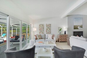 A modern living room with a sofa, coffee table, and chairs, a fireplace, and artwork on the walls.
