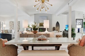 Una sala de estar moderna con una mesa de comedor de cristal, dos sofás, una mesa de centro y una lámpara de araña grande.