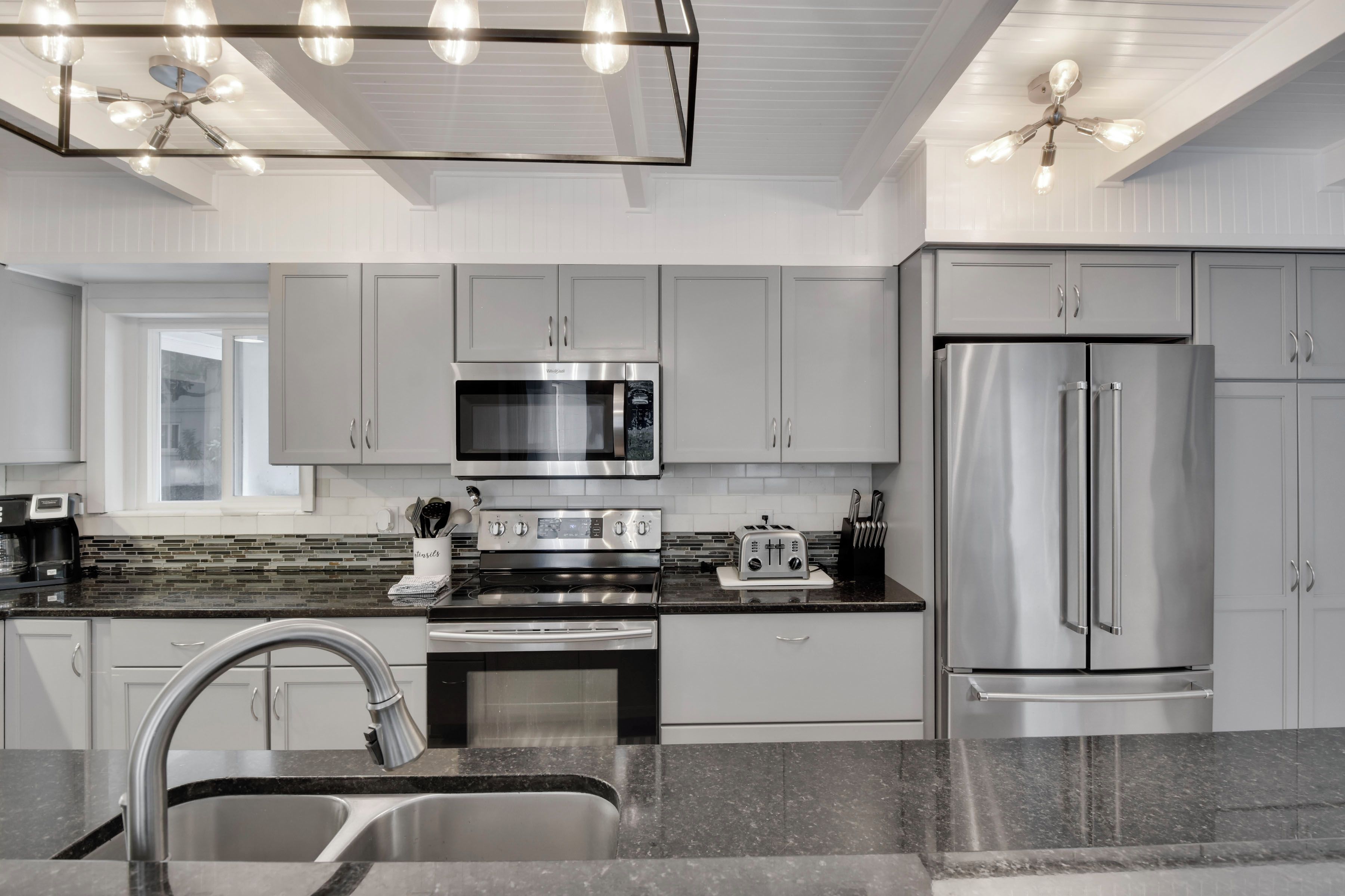 A modern kitchen with stainless steel appliances, a double sink, and a window.