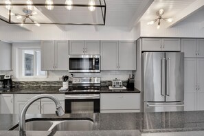 A modern kitchen with stainless steel appliances, a double sink, and a window.