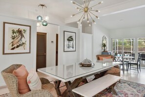 A dining area with a glass table, wicker chairs, and a bench.