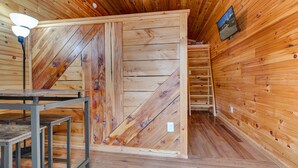 A wooden interior with a large sliding door, a ladder, and a table with metal legs. - Hikers Retreat• Handcrafted Cabin in RRG • PET FRIENDLY• Location is Key  (Pine Ridge)