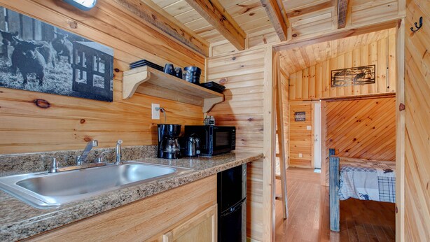 A wooden cabin interior with a kitchen area featuring granite countertops, a sink, and a black dishwasher. - Hikers Retreat• Handcrafted Cabin in RRG • PET FRIENDLY• Location is Key  (Pine Ridge)