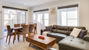 Una sala de estar moderna con comedor, sofá de cuero y una mesa baja con fruta.