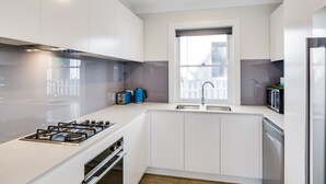 Una cocina moderna con armarios blancos, estufa a gas, microondas y lavavajillas.