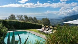 Una piscina con tumbonas y vistas a montañas.