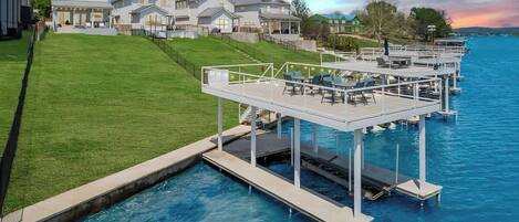 Una propiedad frente al mar con piscina, un área de terraza con sillas y una hilera de casas al fondo.