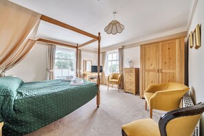 A bedroom with a four-poster bed, a desk, a chair, and a wardrobe. - House - Sleeps 6 & paid off site parking available (Minehead)