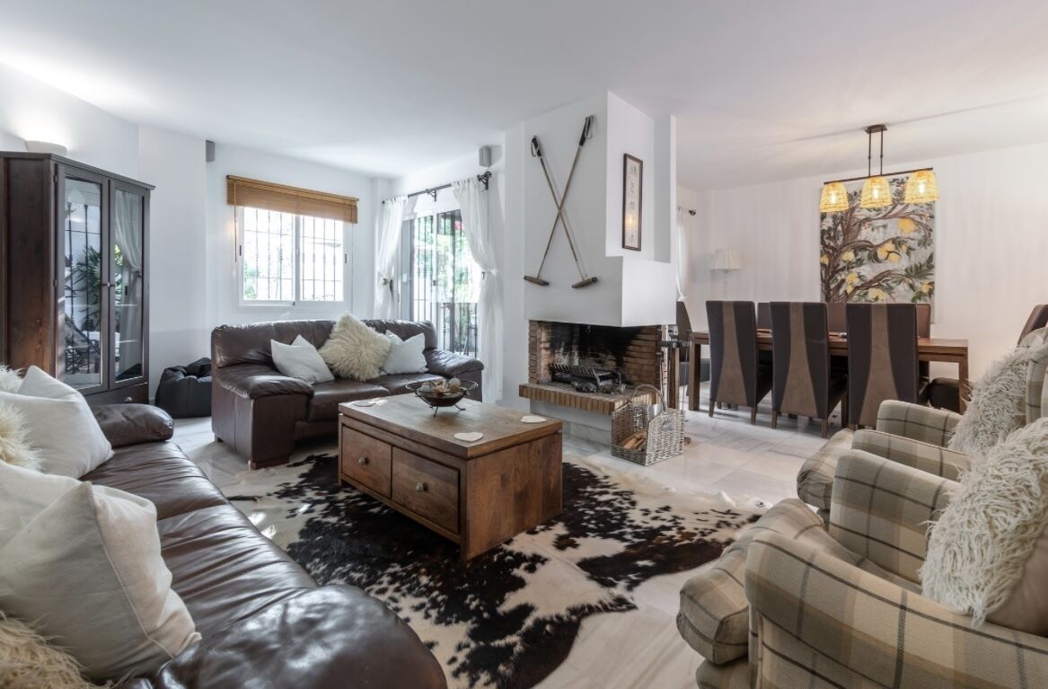 A living room with a fireplace, leather sofas, a coffee table, and a large rug.