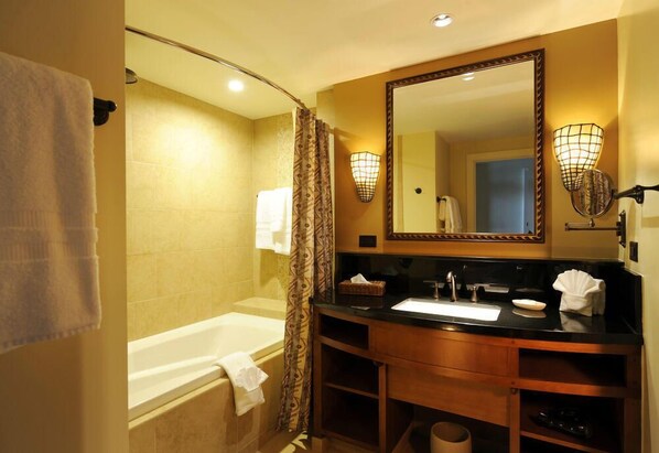 Un baño con bañera, lavabo, espejo y toallero.