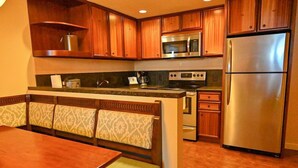 A kitchen with wooden cabinets, stainless steel appliances, and a dining area with a bench.
