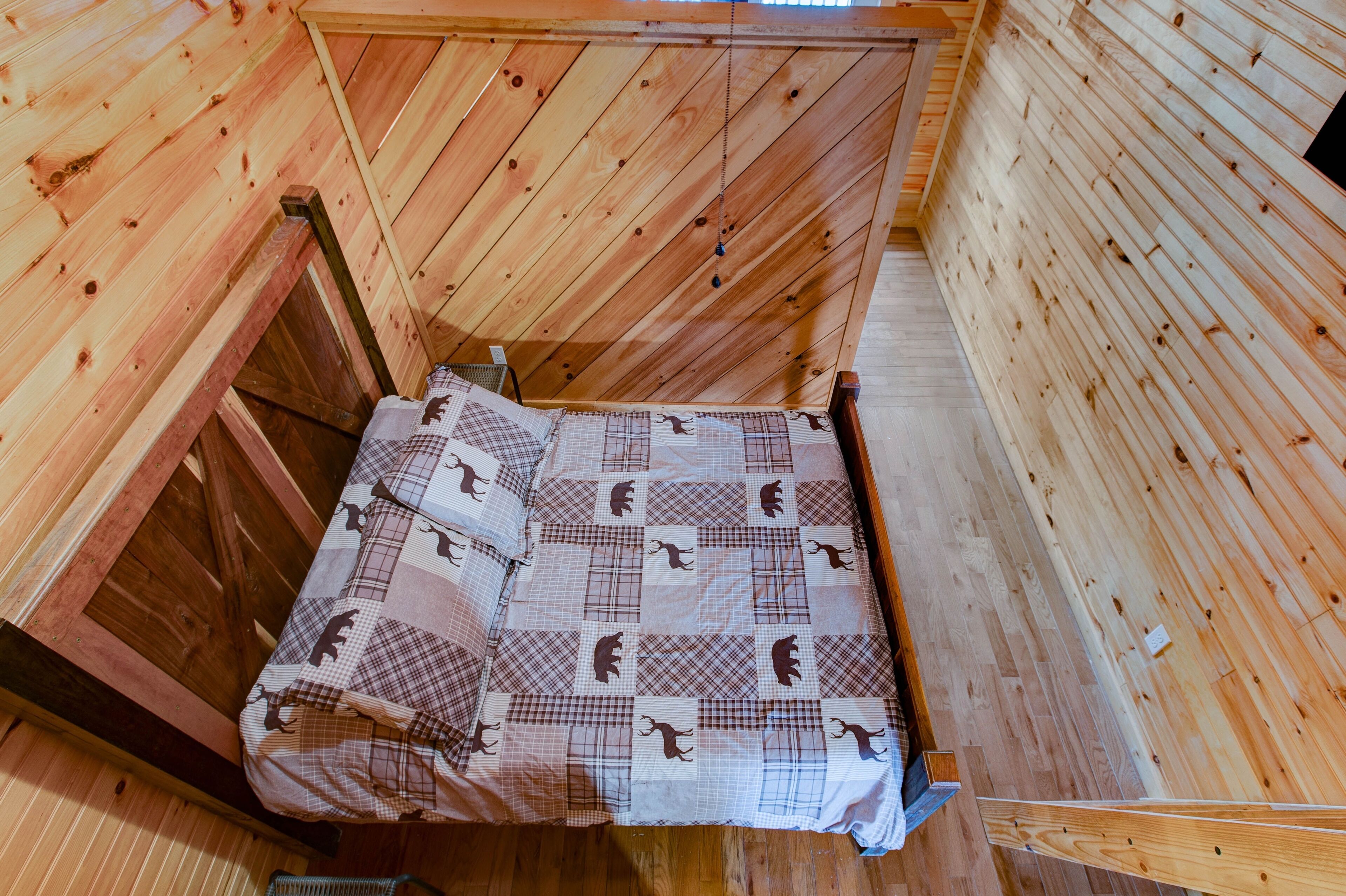A wooden interior with a bed featuring a checkered quilt.