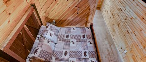 A wooden interior with a bed featuring a checkered quilt.