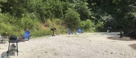 Un espace recouvert de gravier, avec plusieurs chaises Adirondack bleues, un barbecue et une boîte aux lettres.