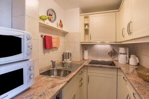 Eine Küche mit Mikrowelle, Spüle und Schränken.