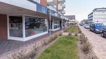 A modern building with a glass storefront, a brick facade, and a landscaped garden area.