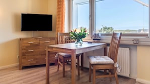 A dining area with a wooden table, chairs, a TV, and a window with a view.