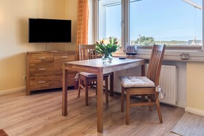 A dining area with a wooden table, chairs, a TV, and a window with a view.