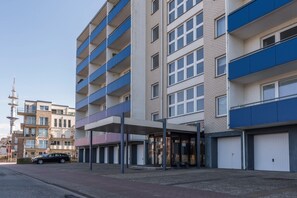 A multi-story hotel with balconies, a covered entrance, and a parking area.