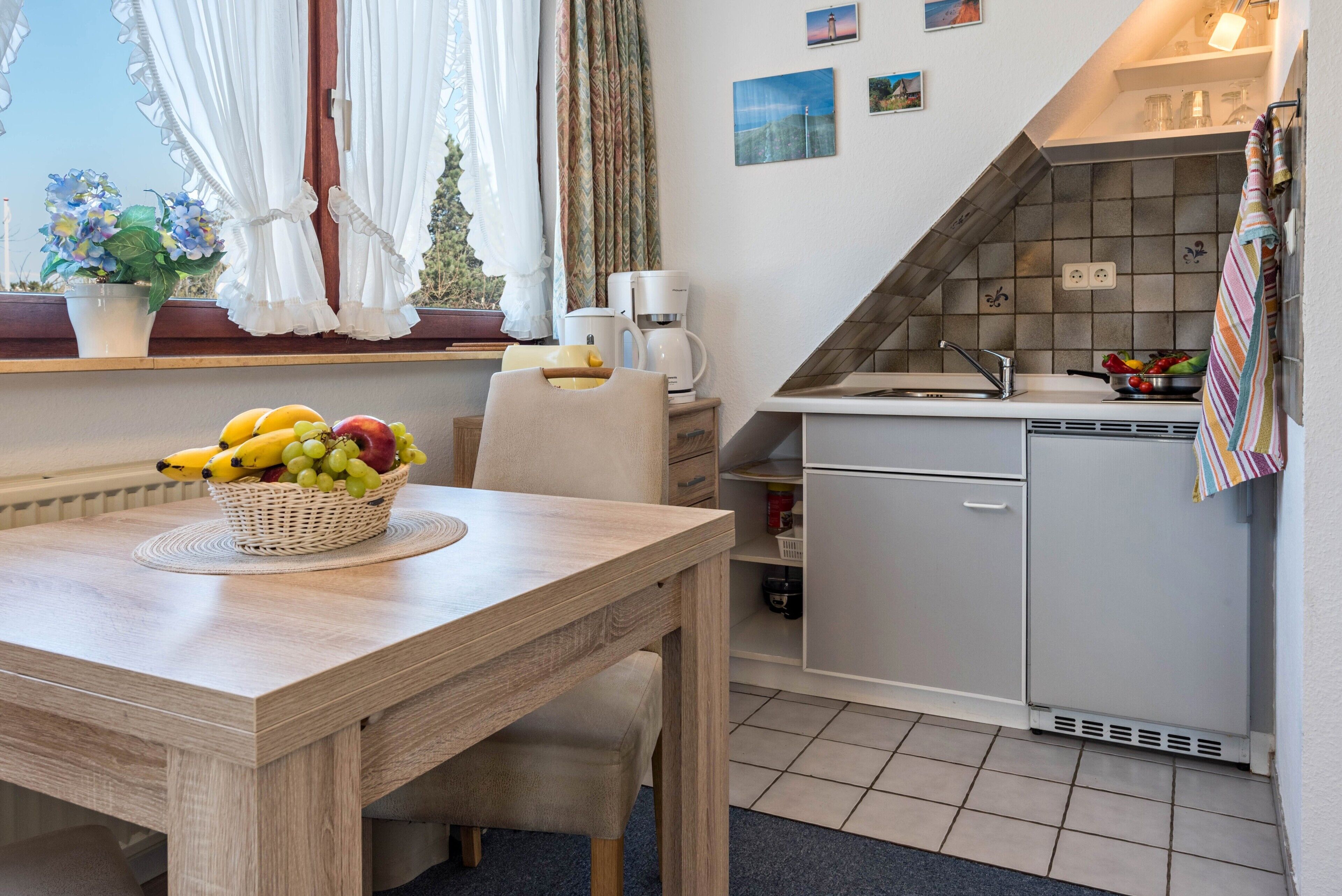 A compact kitchen with a sink, a refrigerator, and a dining area with a table and chairs.