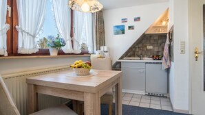 Eine Küche mit Esstisch, Spüle und einem Fenster mit Vorhängen.