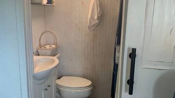 Une petite salle de bain comprenant des toilettes, un lavabo et une petite fenêtre.