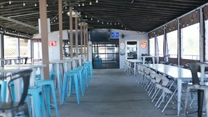 Un amplio comedor interior con techos altos, varias mesas y sillas, y grandes ventanales que dejan entrar luz natural.