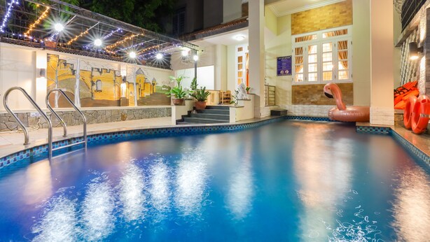A swimming pool with a tiled edge, a metal ladder, and a mural on the wall. - ViVa Villa Vung Tau - Phan Chu Trinh (Ho Chi Minh City)
