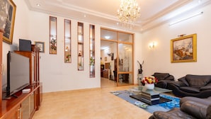 A spacious living room with a television, leather sofa, and a chandelier. - ViVa Villa Vung Tau - Phan Chu Trinh (Ho Chi Minh City)