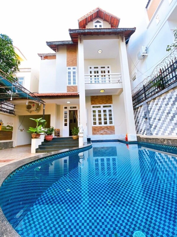 A two-story house with a swimming pool in the foreground.