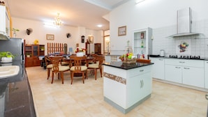 A modern kitchen with white cabinets, a central island, and a dining area with wooden chairs. - ViVa Villa Vung Tau - Phan Chu Trinh (Ho Chi Minh City)