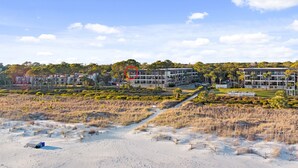 Um hotel à beira-mar com vários edifícios, uma praia de areia e uma área ajardinada com caminhos.