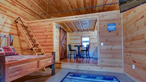 A cabin interior with a bed, a table with chairs, a ladder, and a sign that says "Relax at the Cabin." - Cabin in RRG• Pet Friendly • Hi Speed 🛜 Hikers Welcome (Pine Ridge)