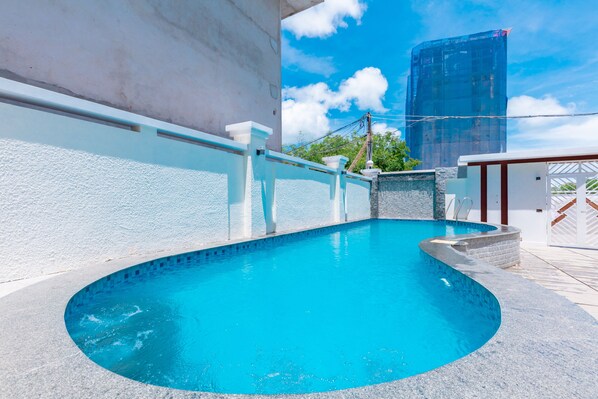A swimming pool with a curved edge, a white railing, and a stone wall.